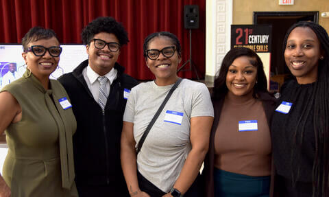 five students standing and smiling 