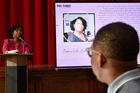 woman in pink dress standing at podium talking